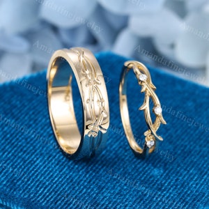 Puede incluir: Un conjunto de dos alianzas de oro con un delicado dise&ntilde;o de vid. La banda de la izquierda tiene un dise&ntilde;o m&aacute;s intrincado con una vid que se envuelve alrededor de la banda. La banda de la derecha tiene un dise&ntilde;o m&aacute;s simple con una vid y tres peque&ntilde;os diamantes.