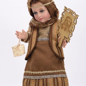 May include: A brown and gold doll dressed in a traditional outfit with a woven basket and a wooden plaque with a carved image.