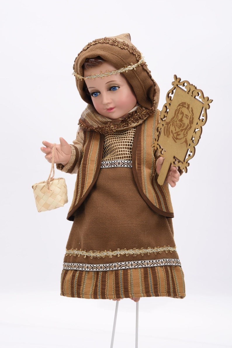 May include: A brown and gold doll dressed in a traditional outfit with a woven basket and a wooden plaque with a carved image.