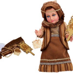 May include: A brown and beige doll dressed in a traditional outfit with a brown head scarf, holding a small basket and a wooden plaque with a carved image. The doll is part of a nativity set.