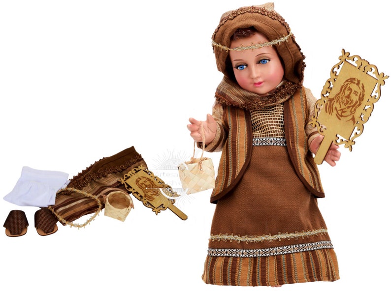 May include: A brown and beige doll dressed in a traditional outfit with a brown head scarf, holding a wooden frame with a carved image of Jesus. The doll is part of a nativity set and includes accessories like a basket, sandals, and a cloth.
