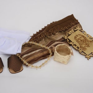May include: A brown and white woven fabric, a white fabric, two brown woven sandals, a small woven basket, and a wooden plaque with a carved image of Jesus.
