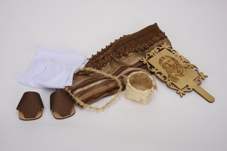 May include: A brown and white woven fabric, a white fabric, two brown woven sandals, a small woven basket, and a wooden plaque with a carved image of Jesus.