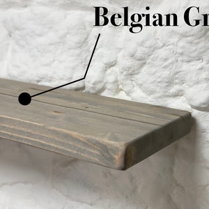 May include: A close-up of a wooden shelf in a gray stain called "Belgian Grey". The shelf is made of natural wood with visible grain and knots.