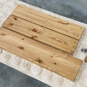 May include: Three unfinished wooden shelves with pre-drilled holes, a small bag of screws, and a screwdriver.
