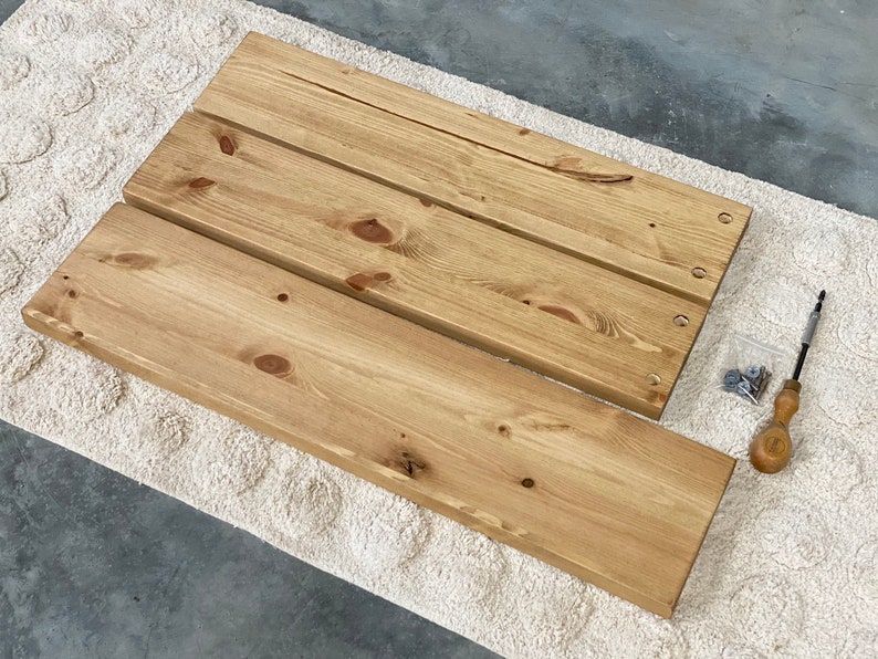 May include: Three unfinished wooden shelves with pre-drilled holes, a small bag of screws, and a screwdriver.