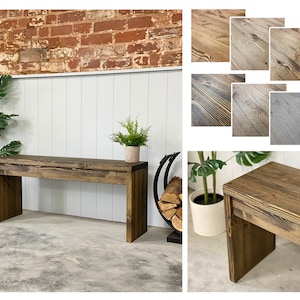 May include: A rustic wooden bench with a dark brown stain. The bench has a simple design with straight legs and a wide, flat top. The bench is made of reclaimed wood and has a natural, distressed look.