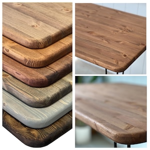 May include: Close-up of five different wood tabletops with rounded edges. The tabletops are stained in various shades of brown, grey, and black.