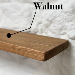 May include: A close-up of a wooden shelf with a natural walnut finish. The shelf is made of solid wood and has a smooth, polished surface.