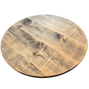 May include: Round wooden table top with a natural wood finish and a distressed look. The top is made of reclaimed wood and has a rustic appearance.