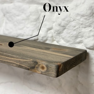May include: A dark gray wooden shelf with a slightly rounded edge. The shelf is labeled "Onyx" in black text.