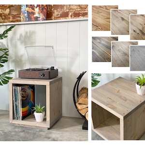 May include: A grey wooden record player stand with a shelf for vinyl records. The stand has a clear plastic lid and a brown record player on top. The stand is sitting on a grey floor.