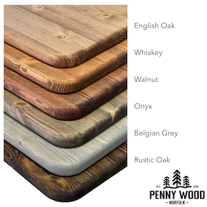 May include: Six wood samples in different shades of brown, gray, and black, stacked on top of each other. The wood samples are labeled with the names of the stains: English Oak, Whiskey, Walnut, Onyx, Belgian Grey, and Rustic Oak. The Penny Wood logo is in the bottom right corner.