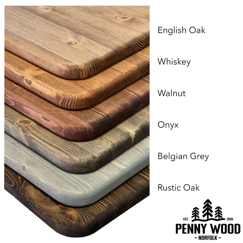 May include: Six wood samples in different shades of brown, gray, and black, stacked on top of each other. The wood samples are labeled with the names of the stains: English Oak, Whiskey, Walnut, Onyx, Belgian Grey, and Rustic Oak. The Penny Wood logo is in the bottom right corner.
