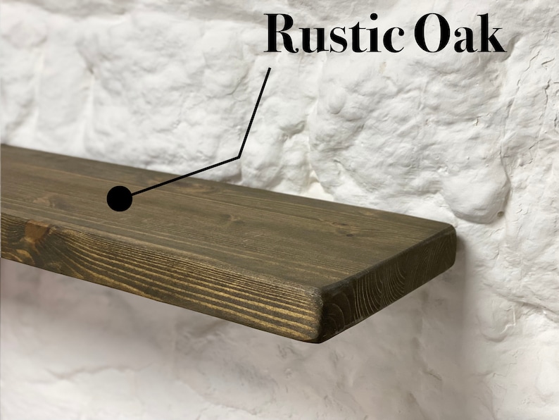 May include: A rustic oak wood shelf with a dark brown stain. The shelf is mounted on a white brick wall.