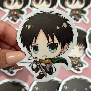 Op de afbeelding: Een set anime-personage stickers met een chibi-stijl personage met bruin haar, groene ogen en een vastberaden uitdrukking. Het personage draagt een bruin en groene outfit en houdt een zwaard vast. De stickers zijn gedrukt op glanzend wit papier.