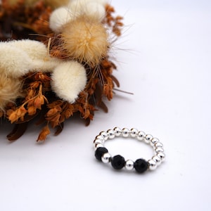 Könnte beinhalten: Ein silberner Perlenring mit drei schwarzen Perlen.