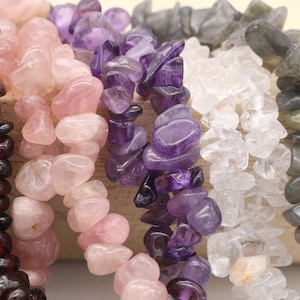 May include: Four strands of chip gemstone beads in various colours. The strands are red, pink, purple, and grey.