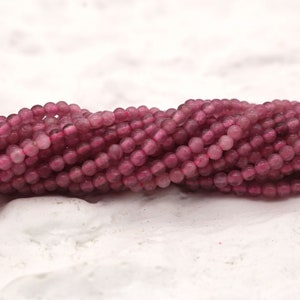 Könnte beinhalten: Eine Strähne aus rosa, mattierten Glasperlen. Die Perlen sind rund und haben eine matte Oberfläche.