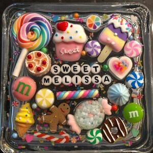 May include: A clear glass square with a colorful resin design featuring candy, sweets, and the name "Sweet Melissa".
