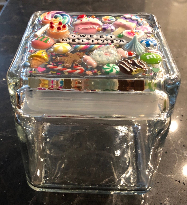 May include: A clear glass jar with a lid decorated with colorful candy and sprinkles. The lid has the words "Sweet Melissa" written on it.