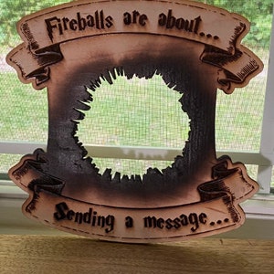 May include: A wooden sign with a burnt-out centre, featuring the text "Fireballs are about... Sending a message..." in a vintage font.