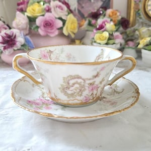 May include: A white ceramic mug with a black handle and the text "But First, Coffee" in a bold, black font. The mug is set against a blurred background, suggesting a cozy setting.