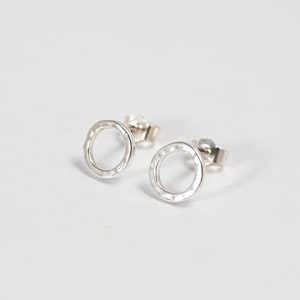 May include: A pair of silver circle stud earrings with a hammered texture.