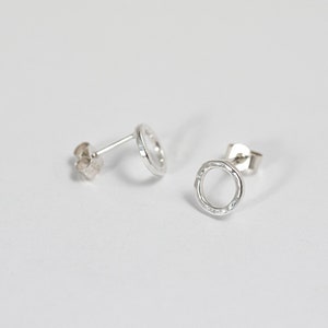 May include: A pair of silver circle stud earrings with a textured finish.