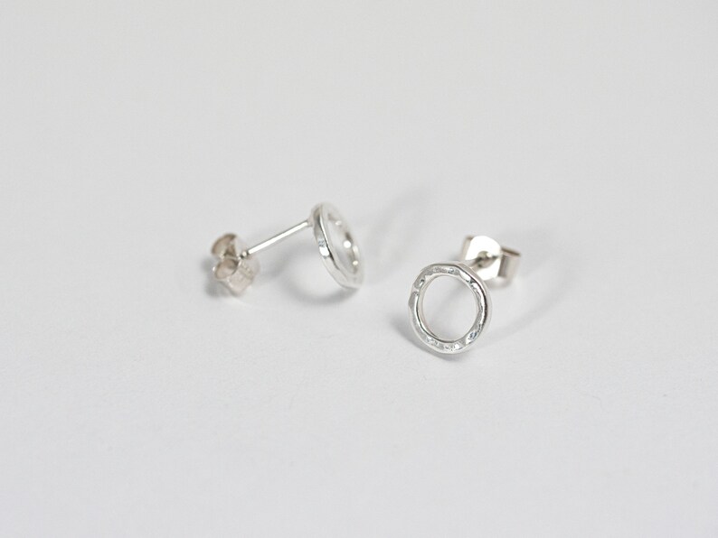 May include: A pair of silver circle stud earrings with a textured finish.