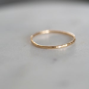 Puede incluir: Un anillo de banda de oro simple con una textura martillada.