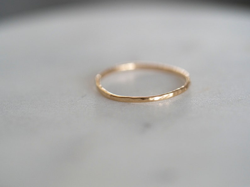 Puede incluir: Un anillo de banda de oro simple con una textura martillada.