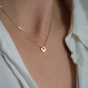 May include: A delicate gold chain necklace with a small, round pendant.