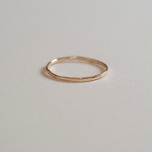 Puede incluir: Un anillo de banda de oro simple con una textura martillada.