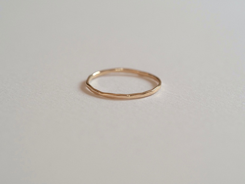 Puede incluir: Un anillo de banda de oro simple con una textura martillada.