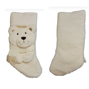 Puede incluir: Un calcetín navideño de felpa color crema con un diseño de oso polar. El oso tiene una cara sonriente, una bufanda color crema y un puño doblado. La segunda imagen muestra la parte posterior del calcetín.