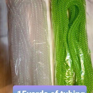 Może przedstawiać: Dwa rolki siatkowego węża, jeden biały z mieniącym się brokatem i jeden jasnozielony, każdy o długości 13,7 metra. Rolki są zapakowane w przezroczysty plastik i oznaczone etykietą "15 yards of tubing".