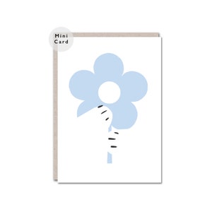 May include: A white card with a blue flower with a white centre and a black stem. The text "Mini Card" is in the top left corner of the card.