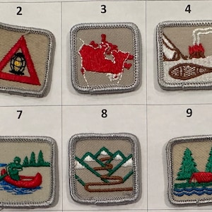 May include: Ten embroidered patches with various designs, including a person with outstretched arms, a triangle with a globe inside, a map of Canada, a campfire scene, a compass, an anchor and flag, a canoe, a mountain scene, and a cabin by a lake. The patches are beige with a grey border.