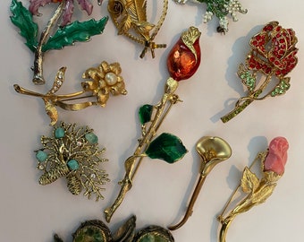 Peut inclure: Une collection de 10 broches florales vintage présentant une variété de styles et de couleurs, notamment le rose, le rouge, le vert, l'or et le blanc.