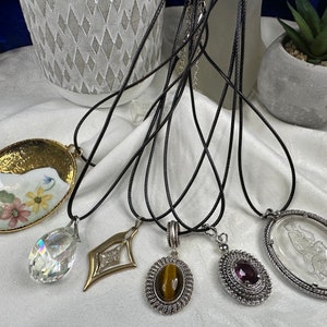 Assorted fashion pendants on black cord necklaces. Each sold separately.