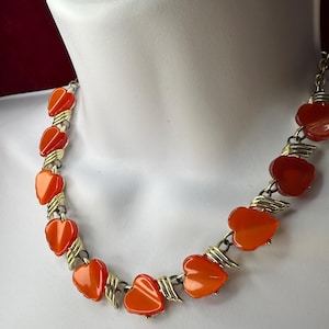 May include: A necklace with a gold chain and orange heart-shaped beads.