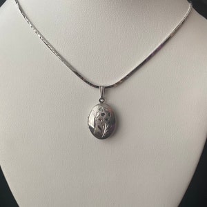 Vintage sterling silver flower engraved oval locket on silver chain.