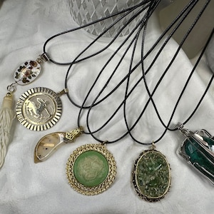 Assorted fashion pendants on black cord necklaces. Each sold separately.