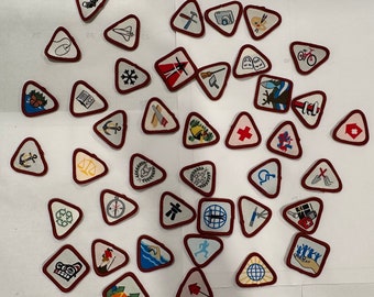 May include: A selection of triangular embroidered patches, each with a white background and a red border. The patches feature diverse designs such as a camera, a bicycle, and a compass, representing different skills and interests.