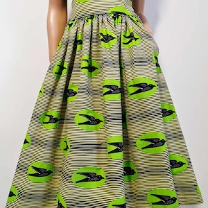 May include: A green and black skirt with a bird print and black stripes. The skirt has a high waist and a full skirt shape.