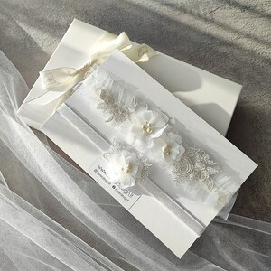 White wedding garter with lace and fabric flowers. Handcrafted with glass pearls and beads. Ready to gift, packed in white box.