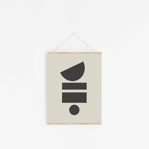 May include: A framed print with a minimalist geometric design. The print features a black half-circle, two black rectangles, and a black circle on a light green background.