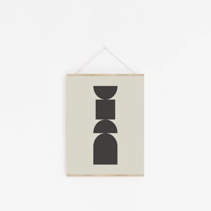 May include: A framed print with a minimalist design featuring a stack of black geometric shapes on a light green background.