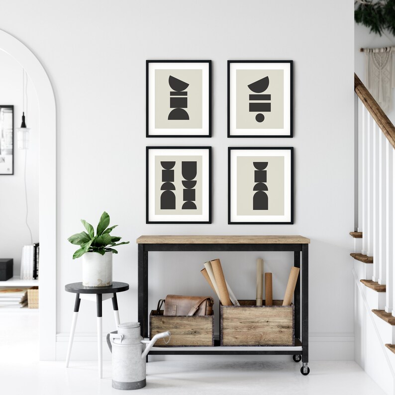 May include: Four black and white abstract geometric prints with a beige background. The prints are framed in black and arranged in a grid pattern on a white wall.